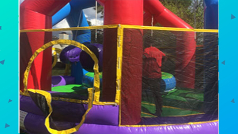 A vibrant Red Wrecking Ball inflatable with mesh sides and a circular entrance is shown outdoors on a sunny day, making it an ideal interactive game rental for events in Wilmington, NC. Bounce house rentals Wilmington NC - Funtime Inflatables NC